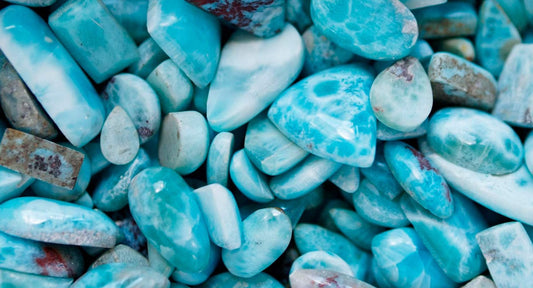 A pile of raw Larimar stones showing their natural blue and turquoise tones