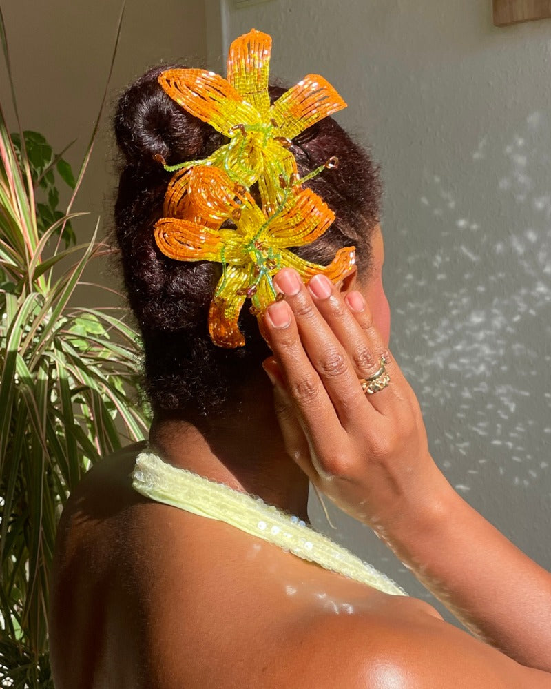 Model wearing two handmade orange French beaded flower hair pins