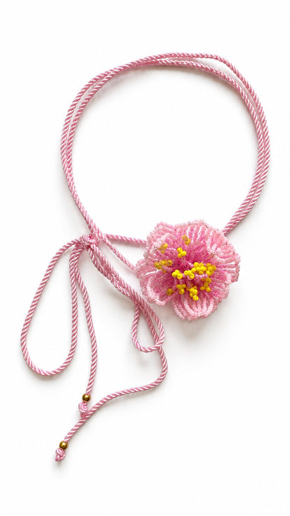 Choker Rosa de Bayahibe de Pamabela: flor de mostacillas rosas con centro amarillo hecha a mano sobre un cordón trenzado rosa con cuentas doradas, vista 1 de 3